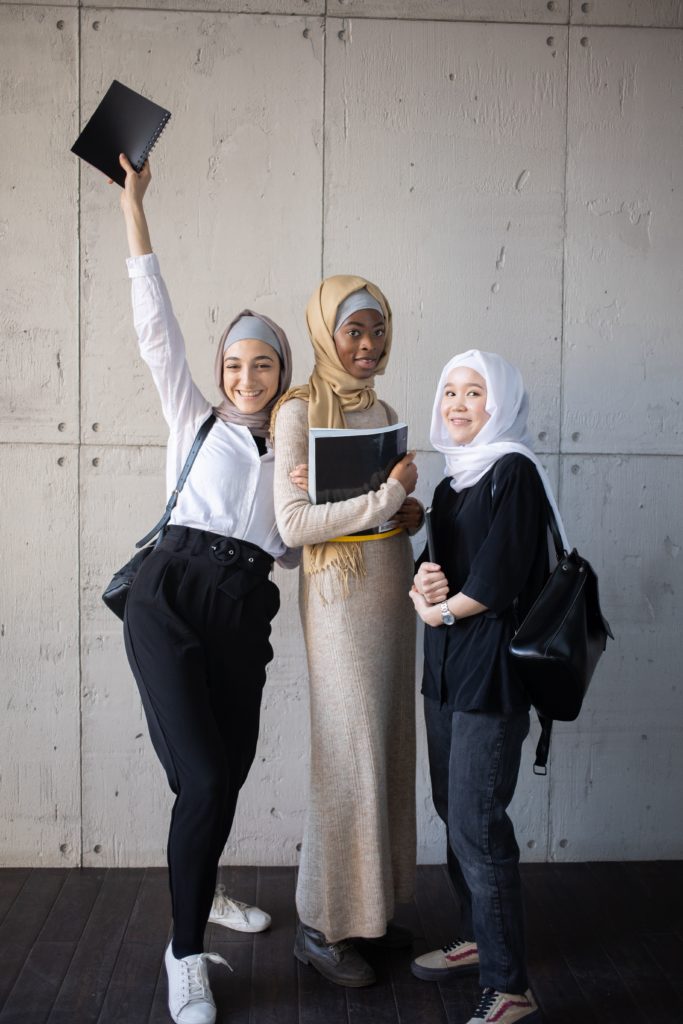 three muslim girls students with backbags and books  smiling